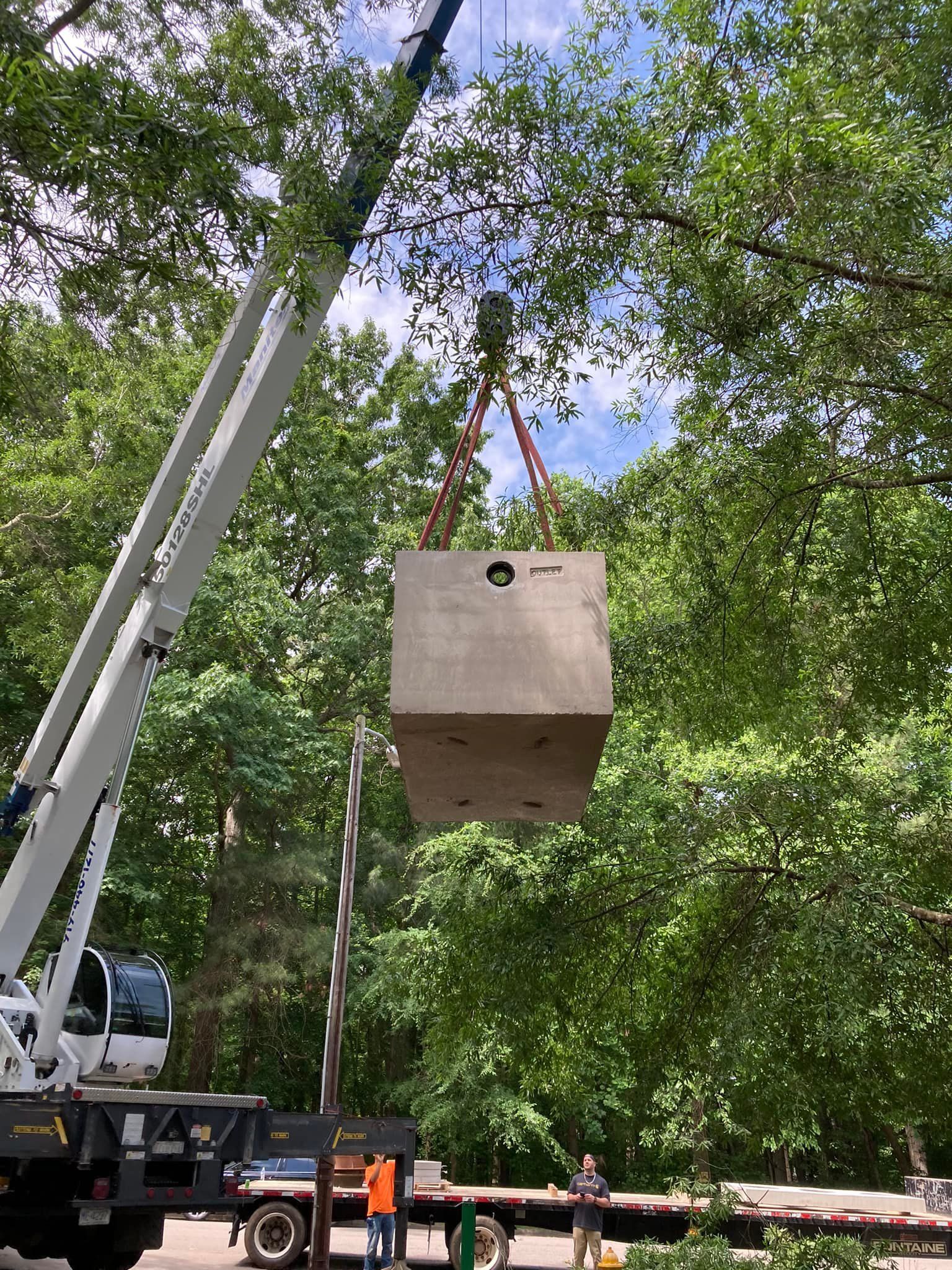 A large concrete block is being lifted by a crane.