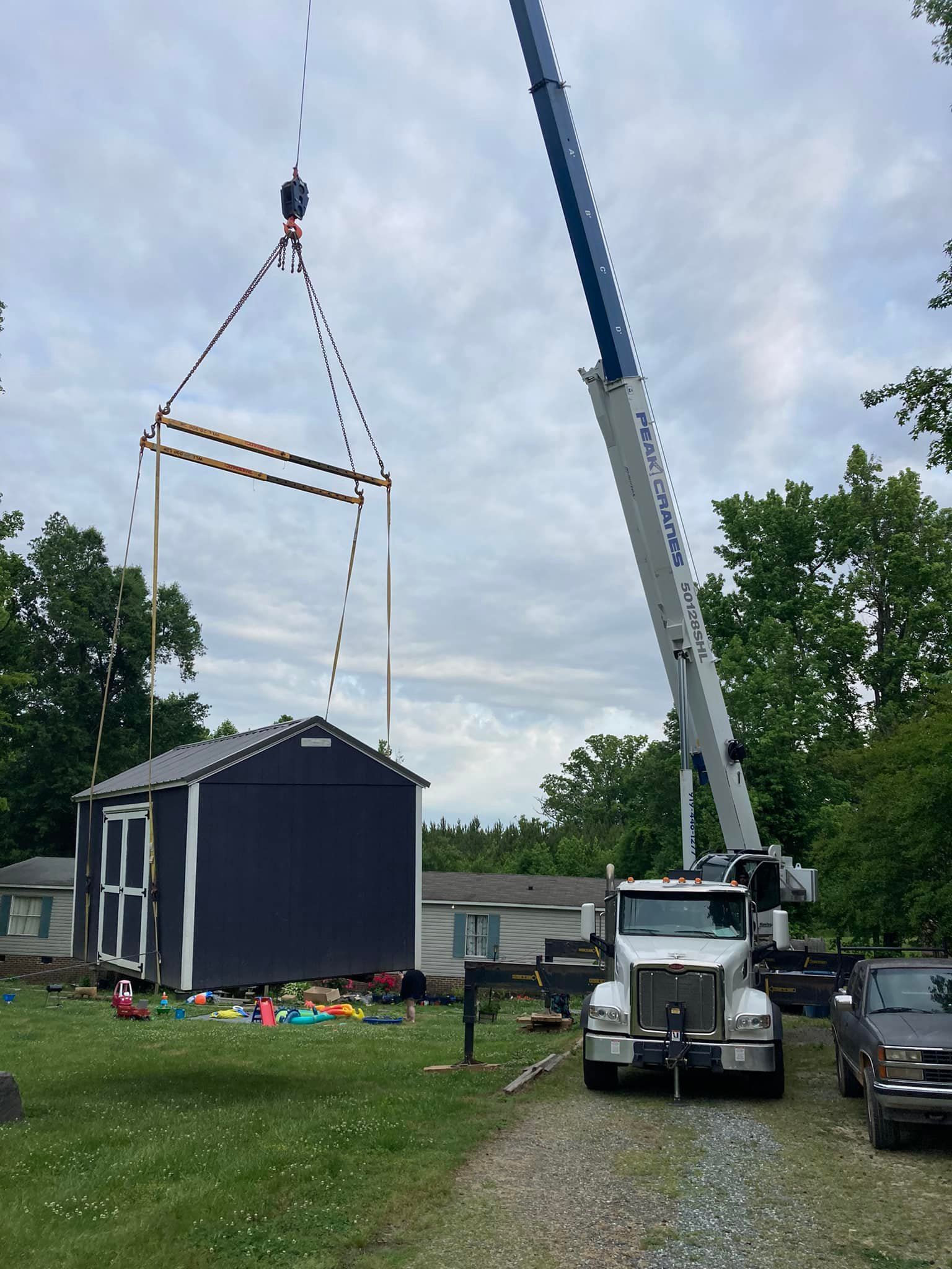 A crane is lifting a shed in a yard.