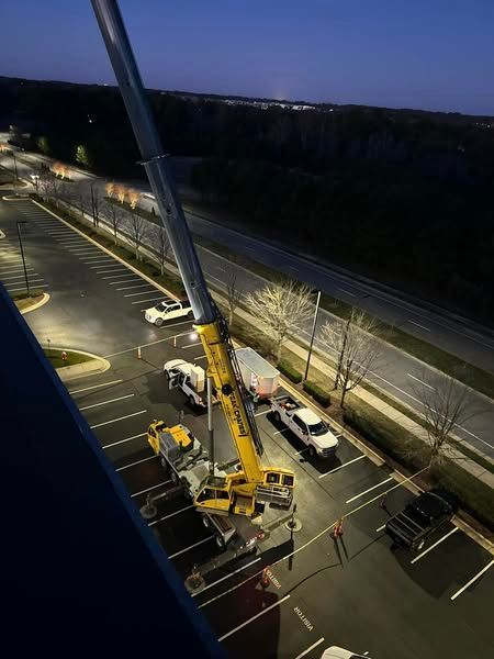 A large yellow crane is sitting in a parking lot at night.