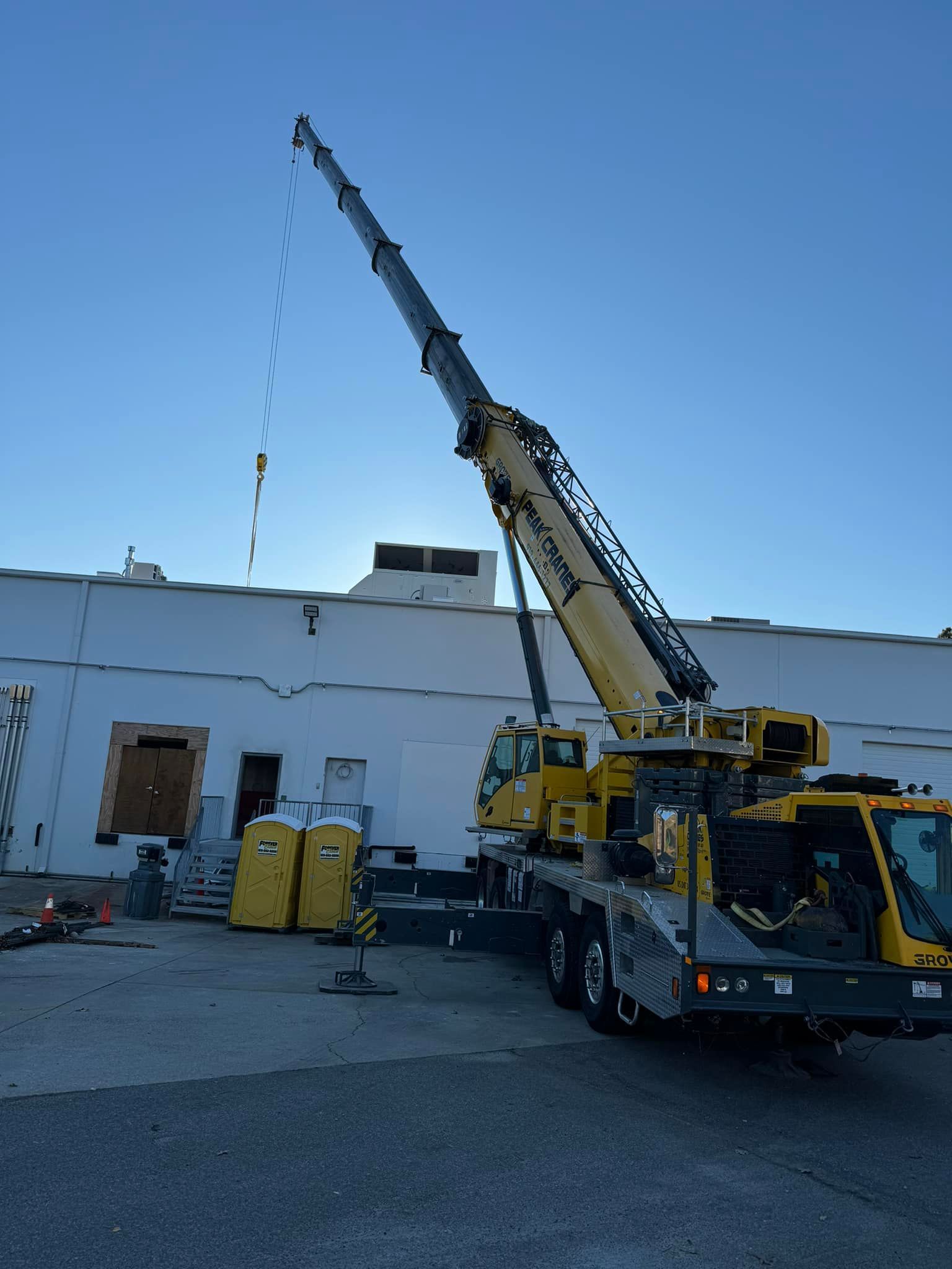 A large yellow crane is parked in front of a white building