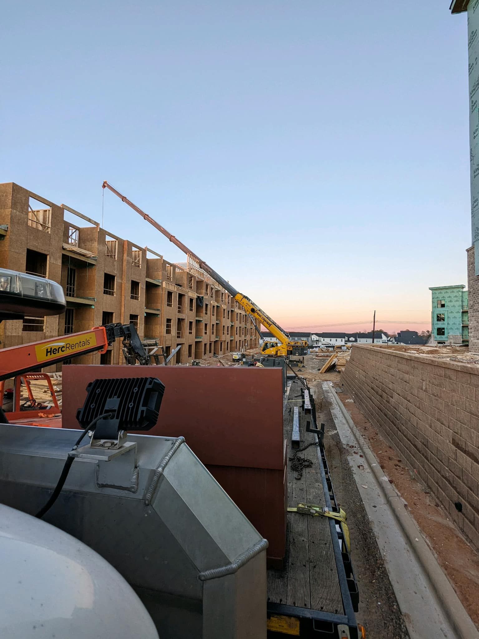A construction site with a crane in the foreground and a building in the background.