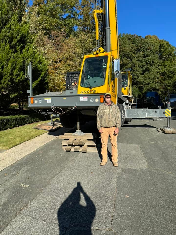 A man is standing in front of a large yellow crane.