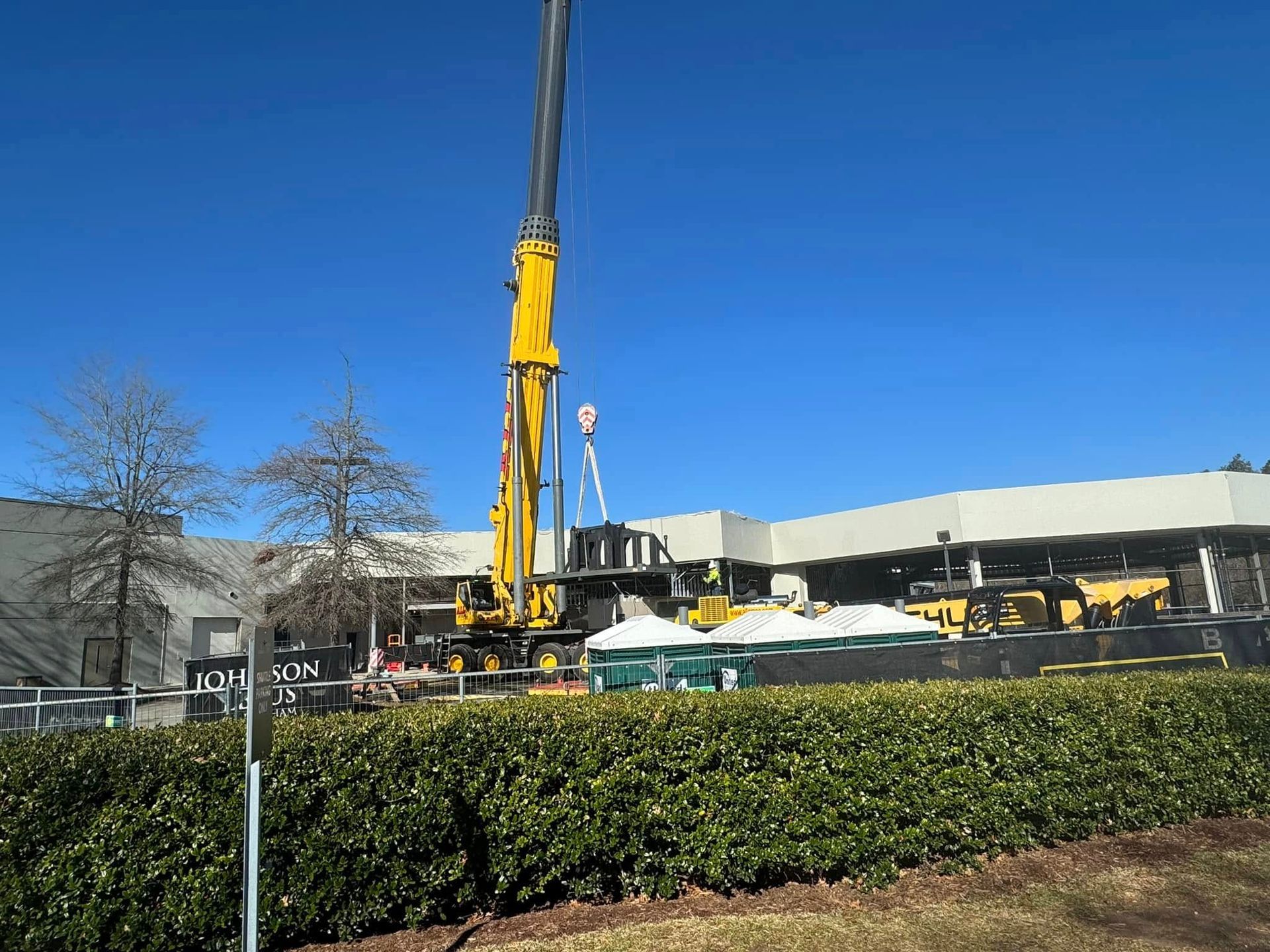 A large yellow crane is sitting in front of a building.