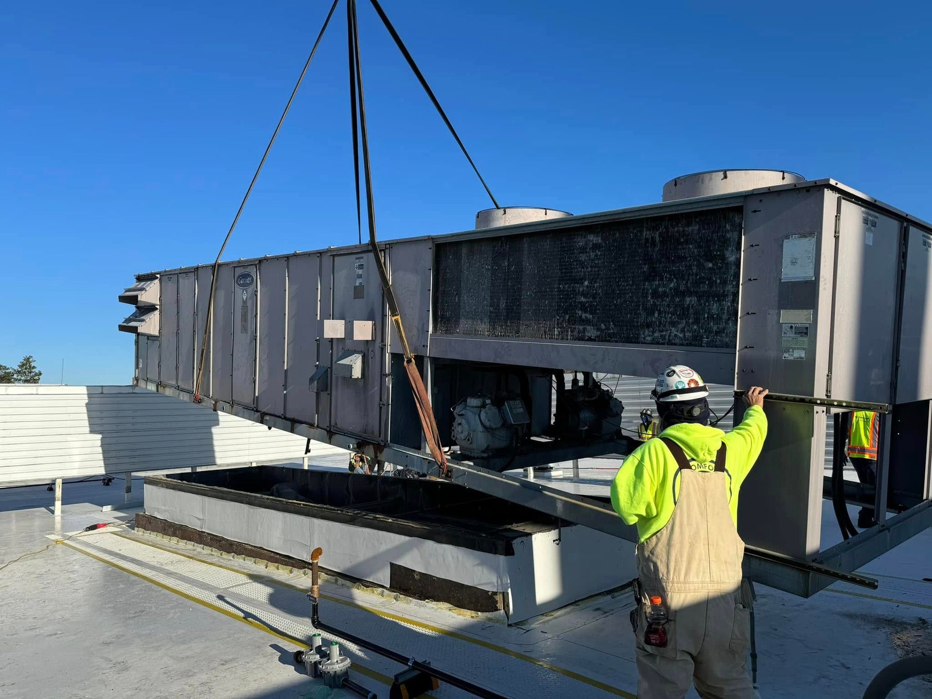 A man is lifting a large piece of equipment on top of a building.