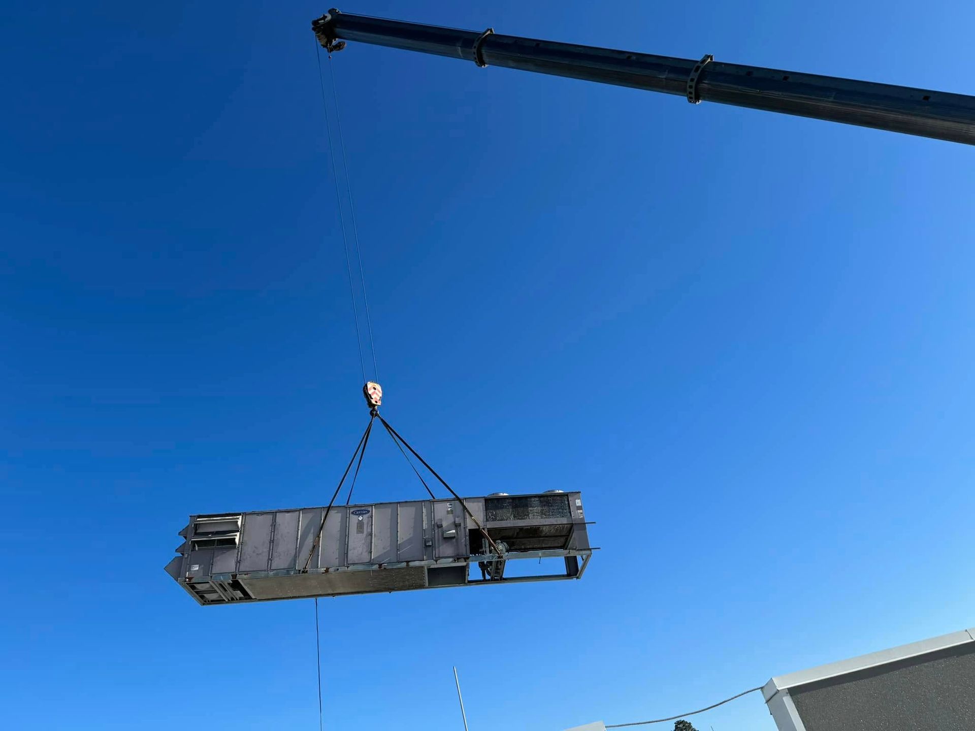 A large piece of metal is being lifted into the air by a crane.