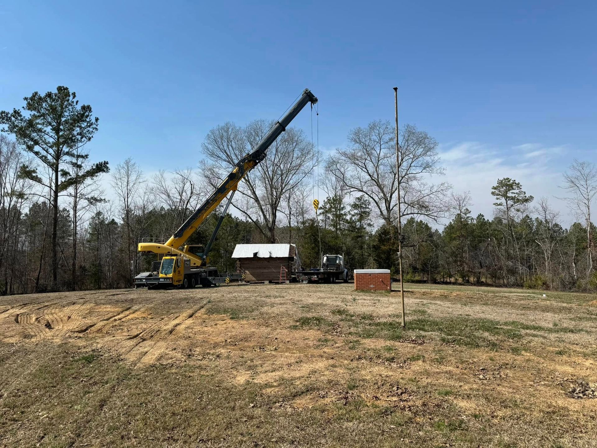A large yellow crane is sitting in the middle of a field.