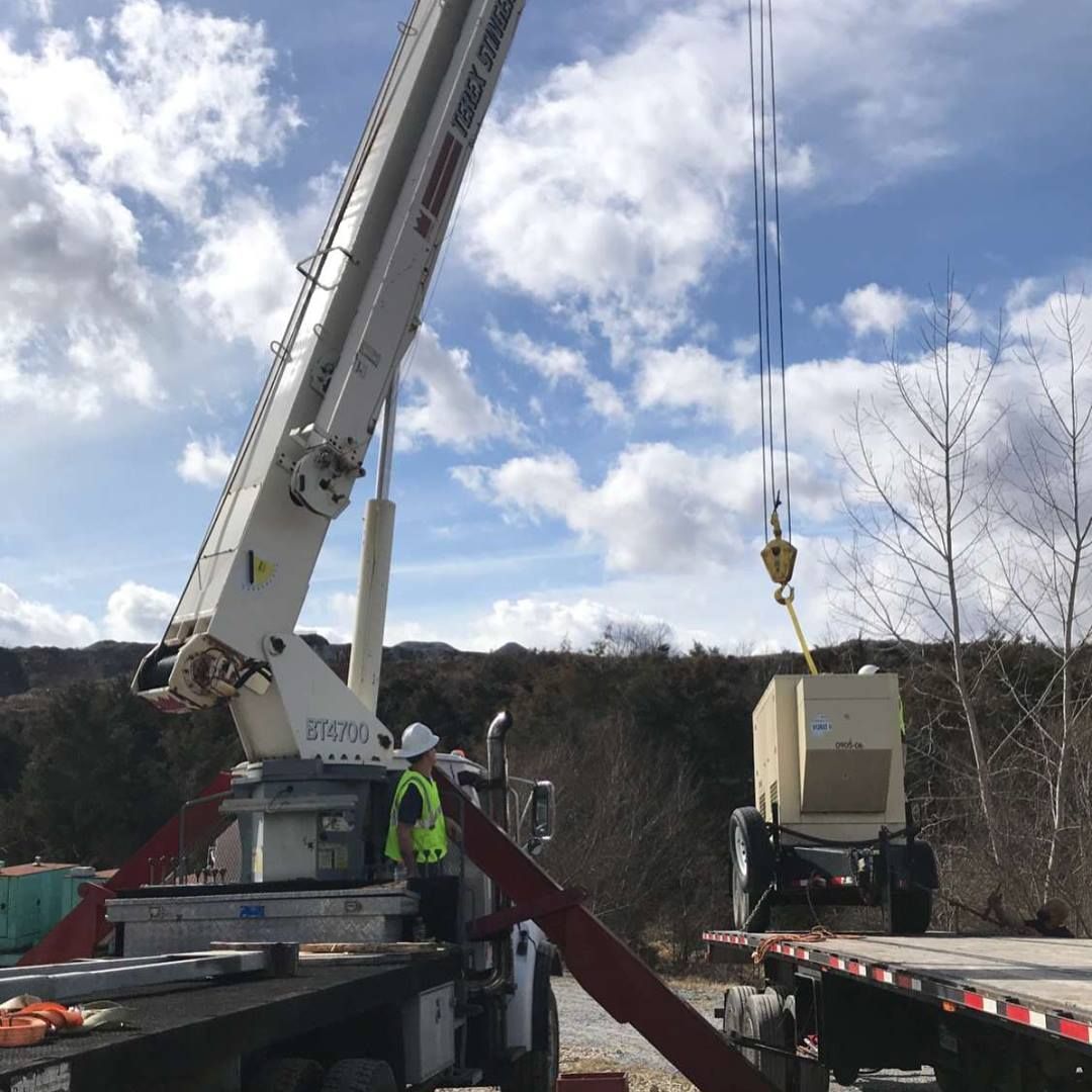 A crane is lifting a box on top of a truck