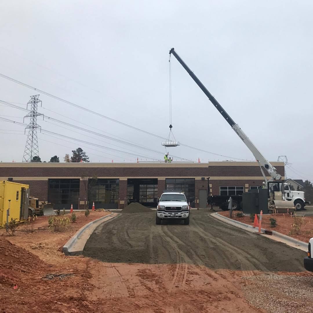 A truck is driving down a dirt road in front of a building under construction.