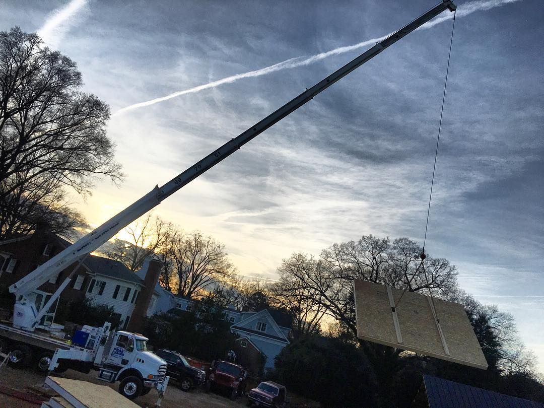A crane is lifting a large piece of wood in the air.