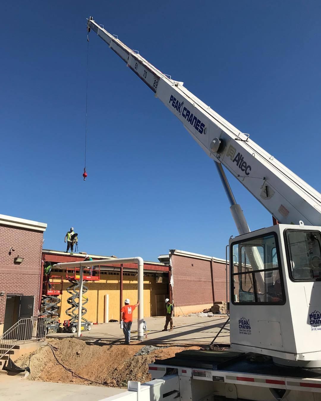 A large crane is being used to lift a metal structure on top of a building.