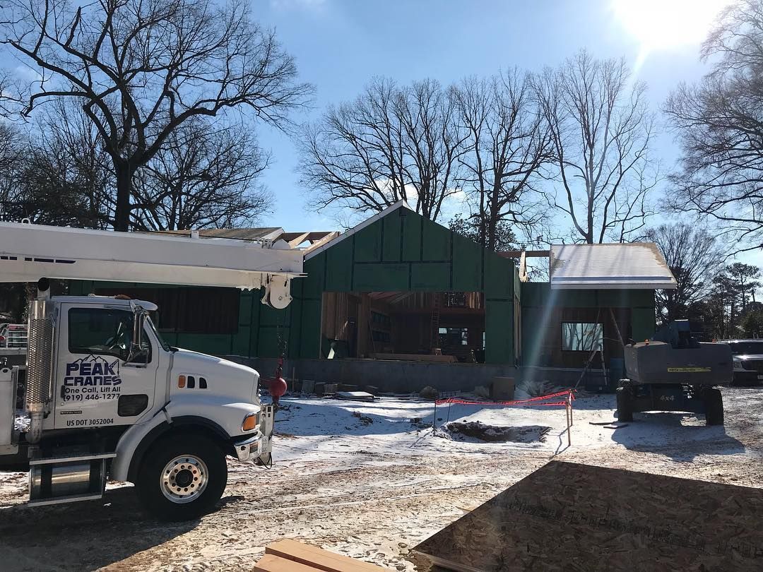 A construction truck is parked in front of a house under construction.