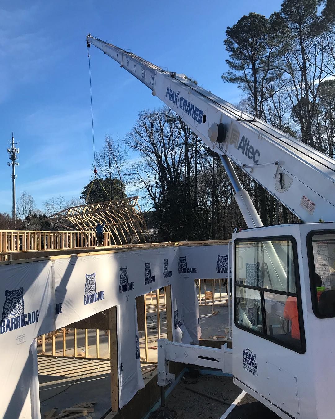 A white crane is sitting on top of a building under construction.