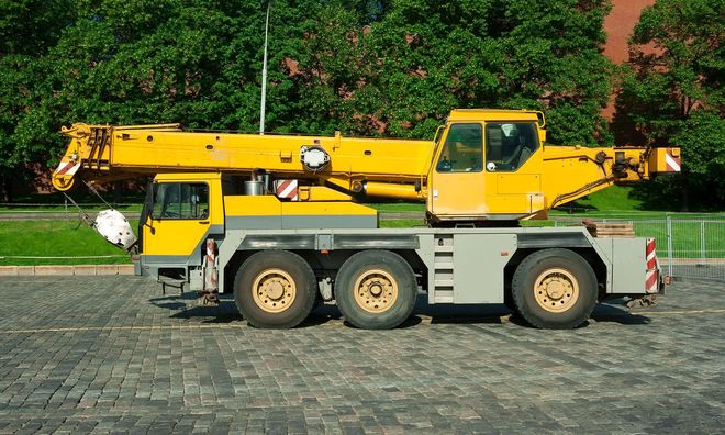 A large red and white crane truck is parked in a dirt lot.