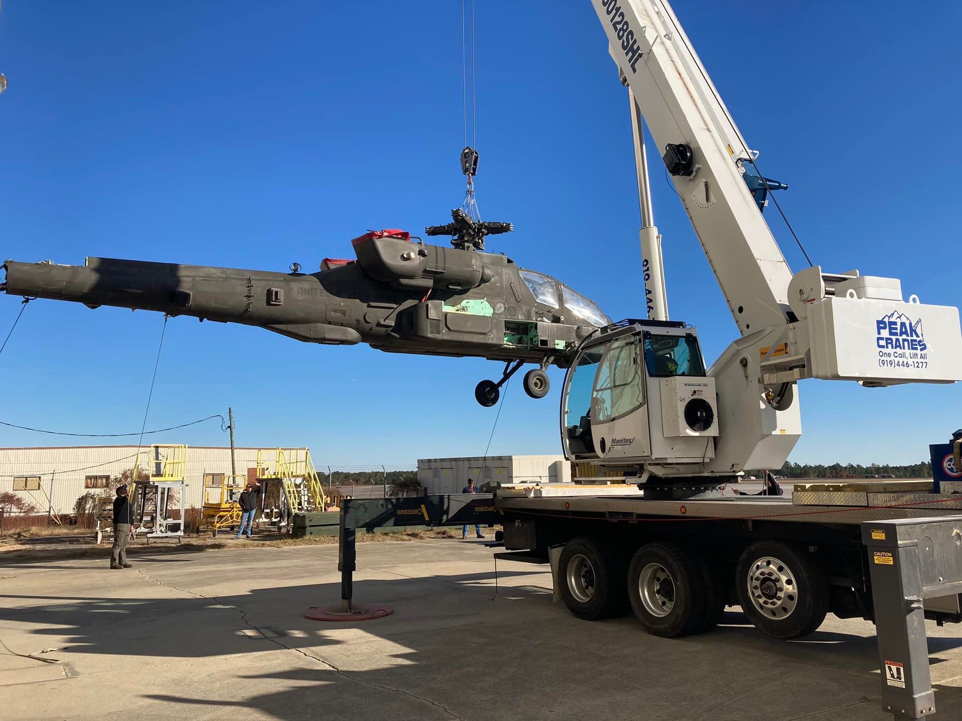 A helicopter is being lifted by a large crane.