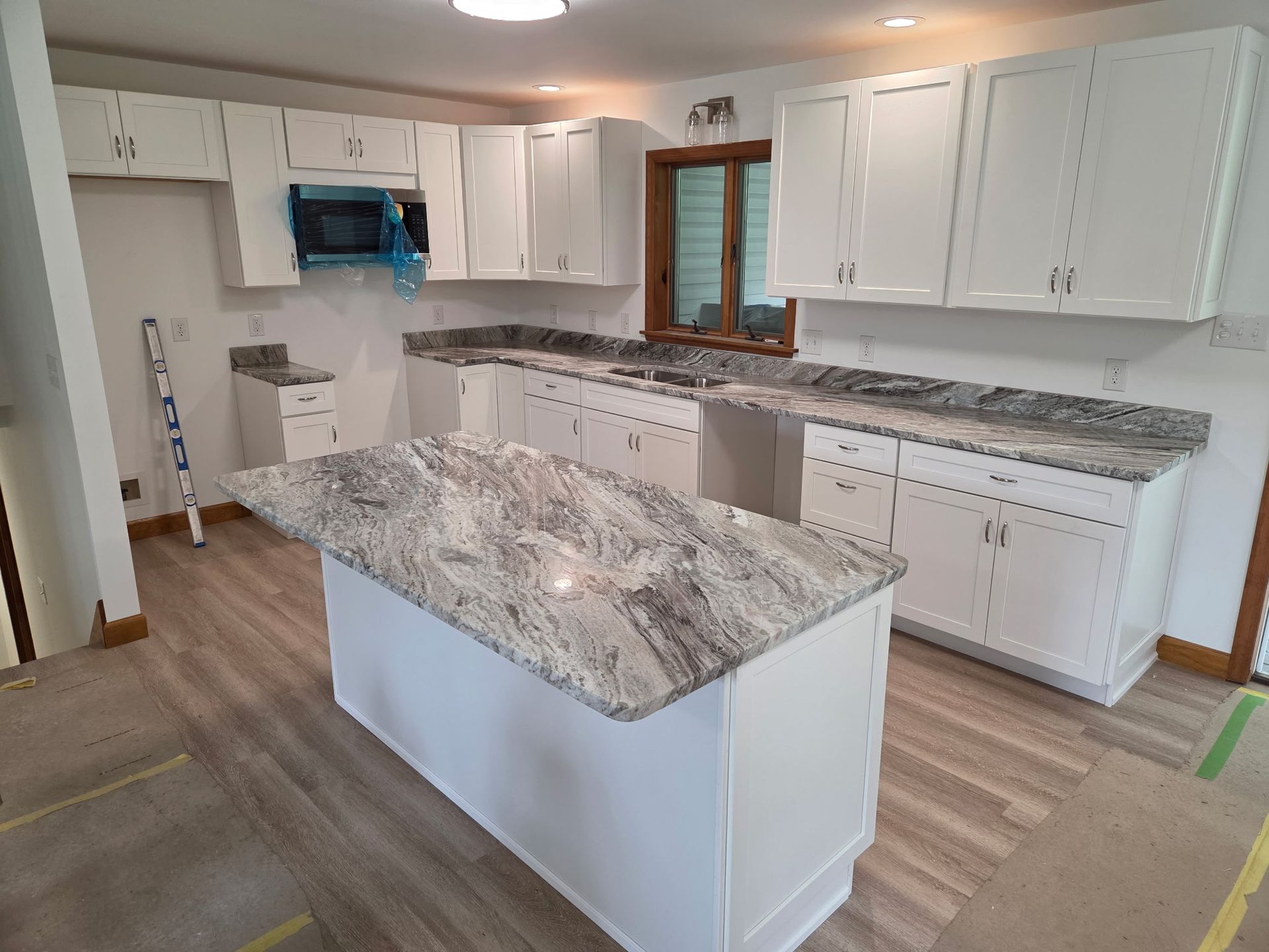 Modern kitchen with white cabinets, granite countertops, and a central island with matching stone top