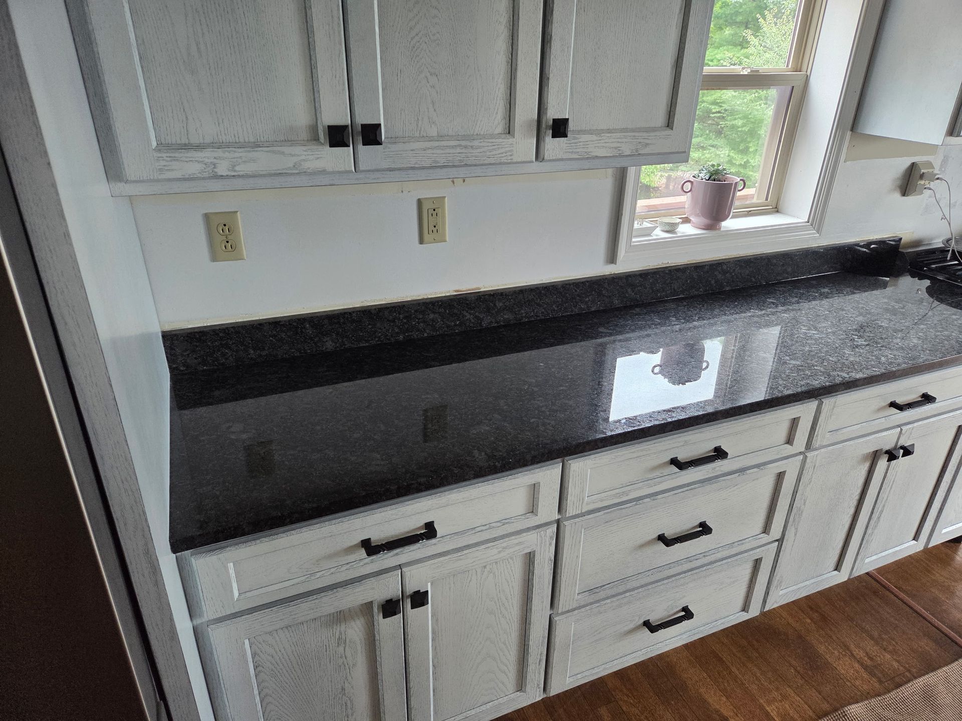 Kitchen with black granite countertop, white cabinets, and a window above the sink.