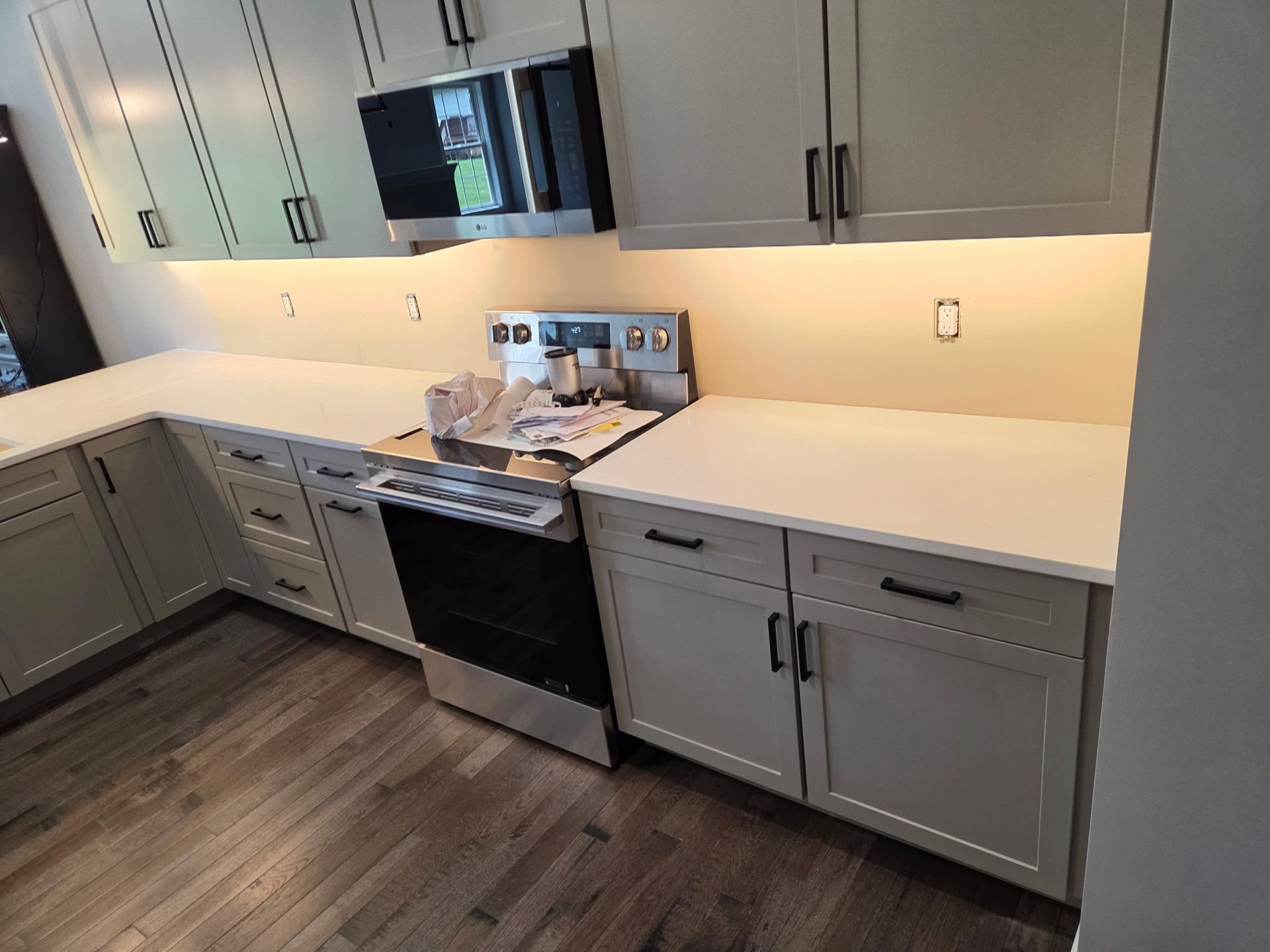 Modern kitchen with gray cabinets, white countertops, stainless appliances, and wood-look flooring
