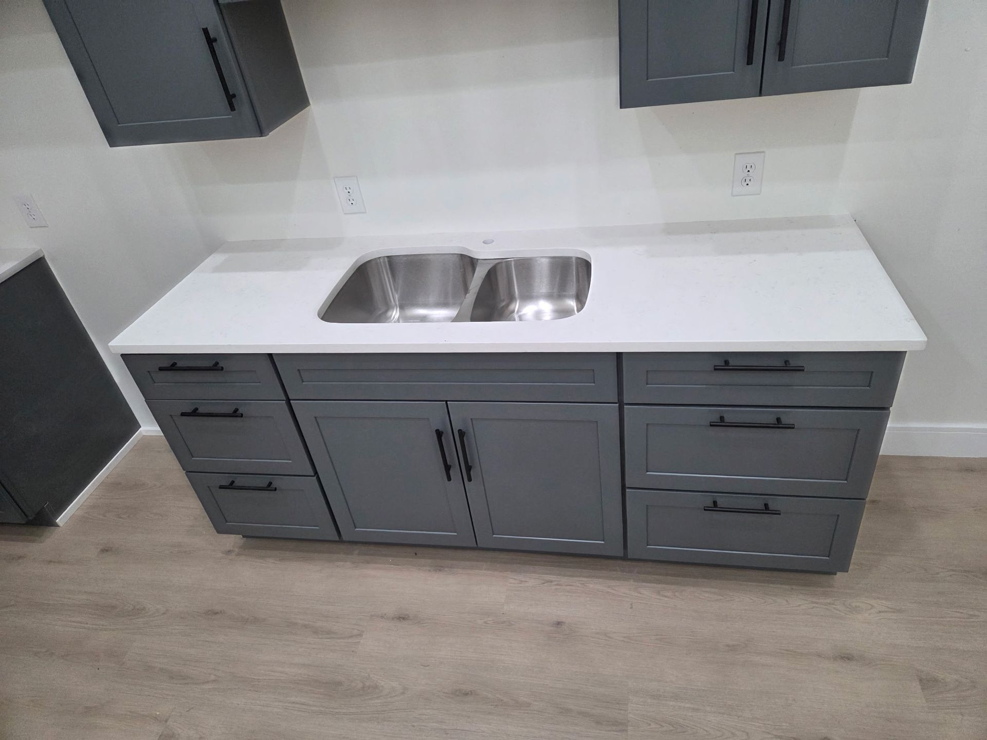 Gray kitchen cabinets with white countertop and double sink in a modern room