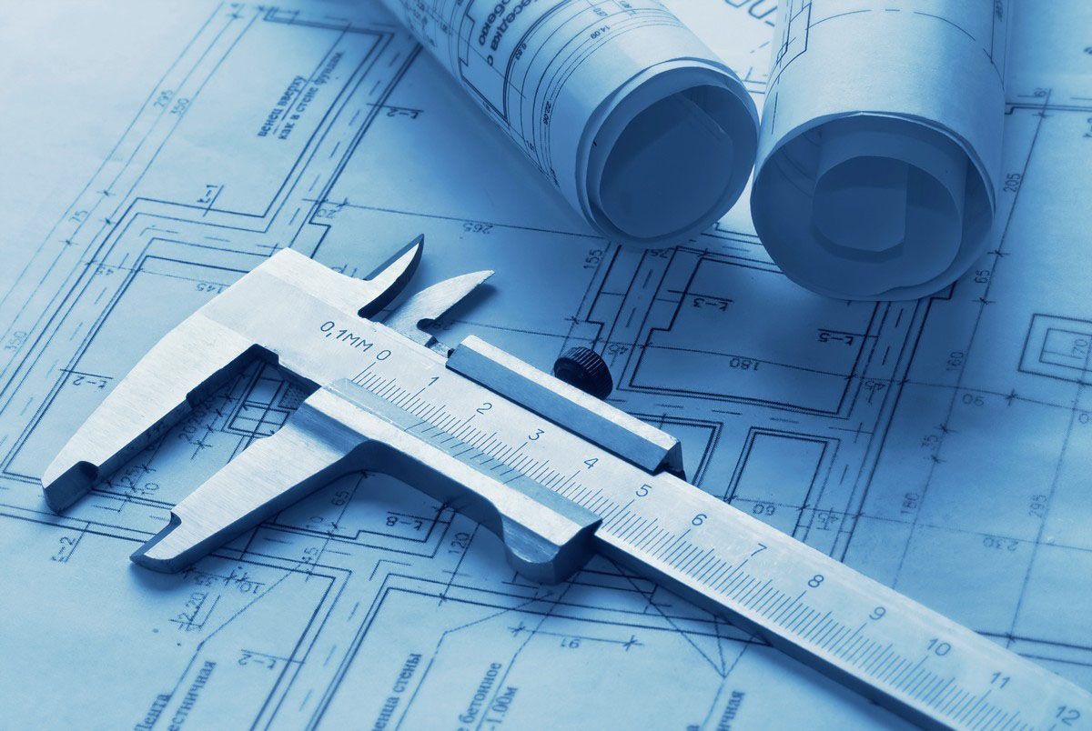 Blueprints with a vernier caliper and rolled plans on a drafting table