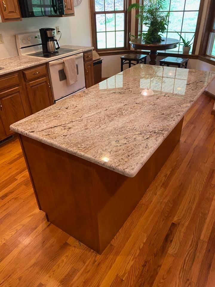 Kitchen island with granite countertop and wooden cabinets; hardwood floors.