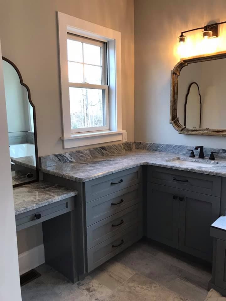 Gray bathroom vanity with granite countertop, window, and two mirrors.