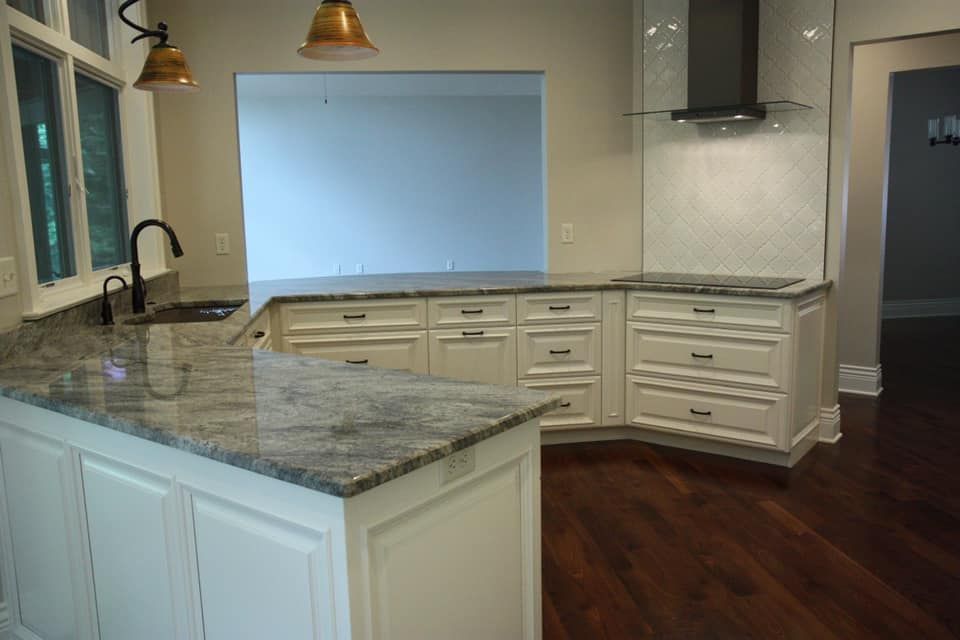Kitchen with white cabinets, gray countertop, and dark wood floors.