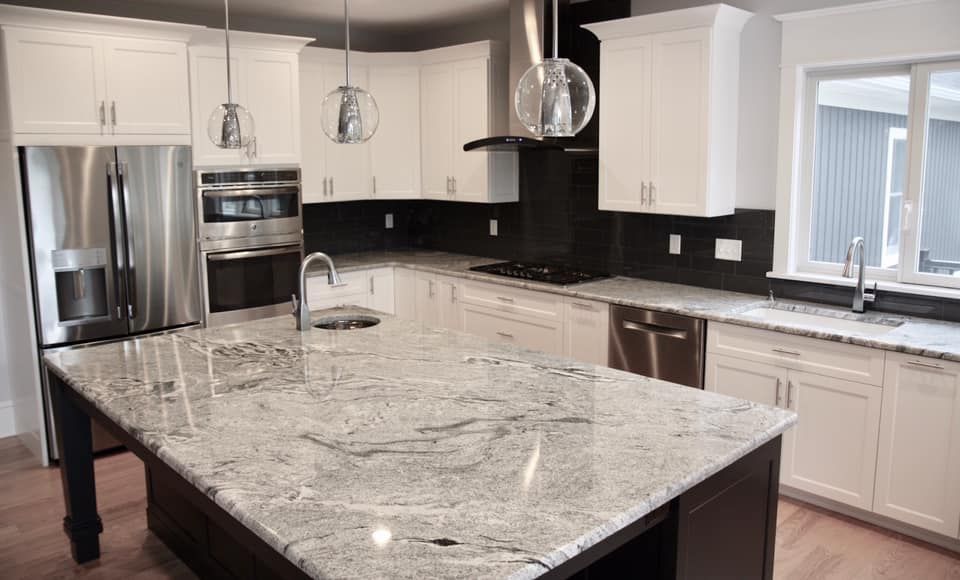Modern kitchen with white cabinets, dark countertops, and granite island.