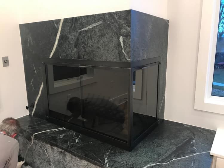 Modern fireplace with dark green marble surround and black glass enclosure.