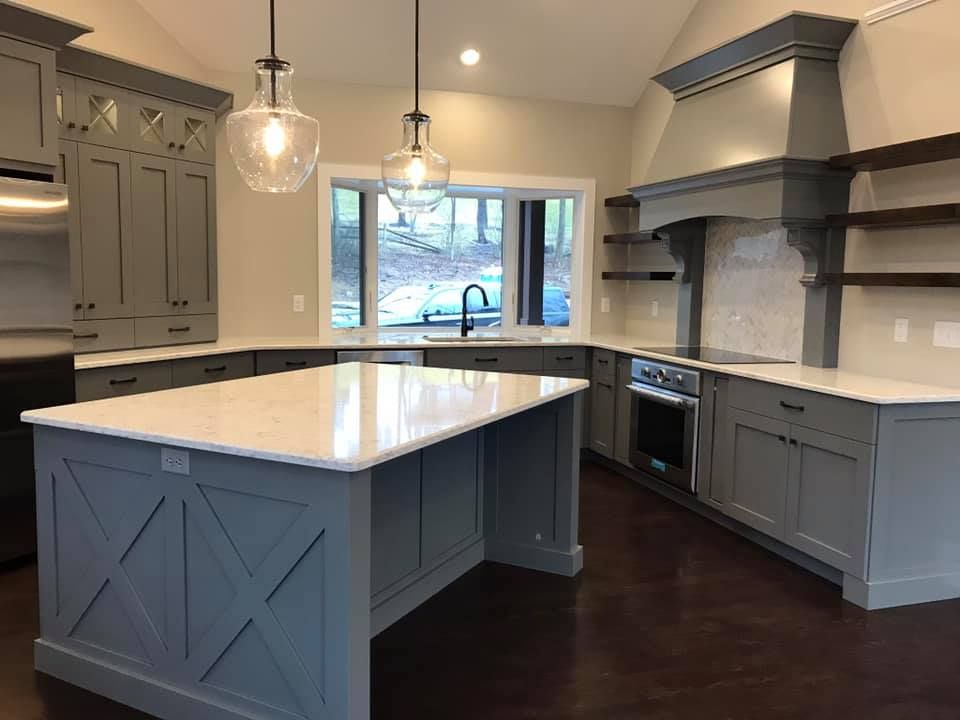 Gray kitchen with white countertops and island, pendant lights, and stainless steel appliances.