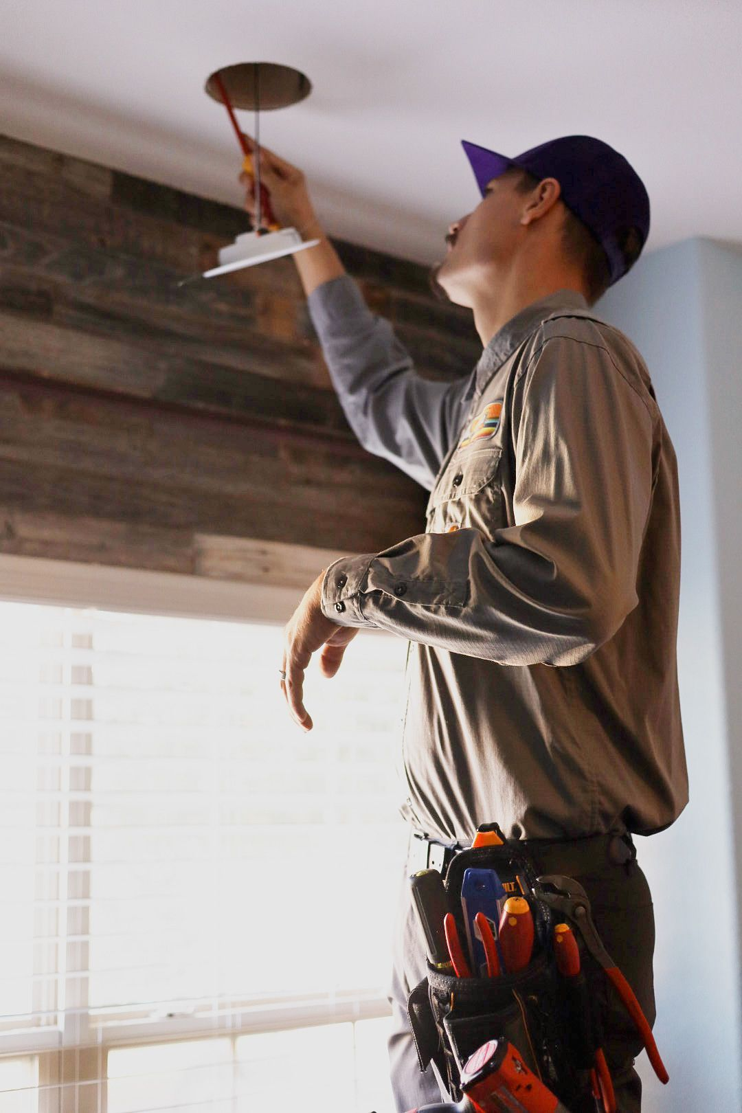 A man is working on electrical wires on the ceiling