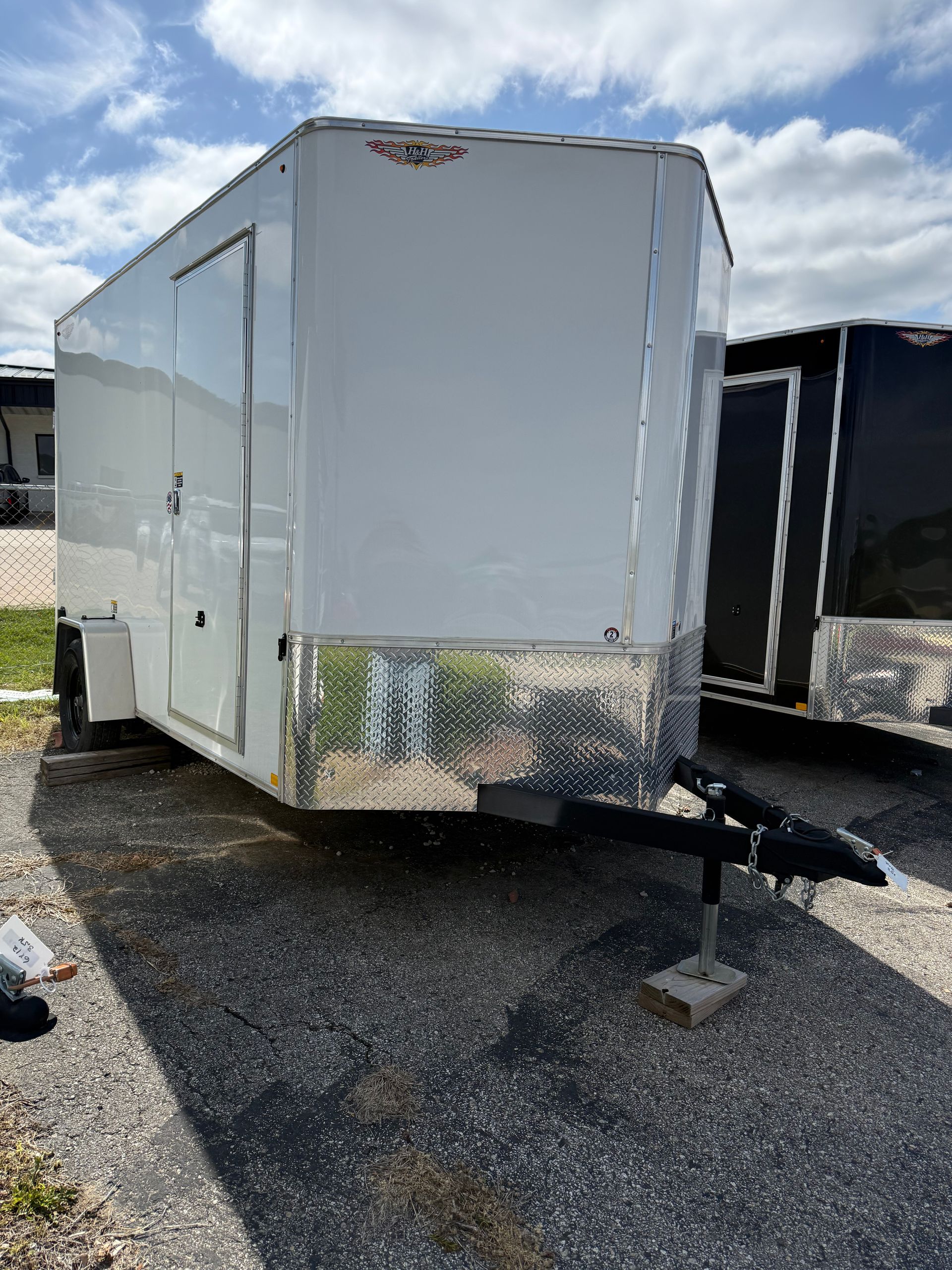 Black flatbed trailer with two axles parked on cracked pavement