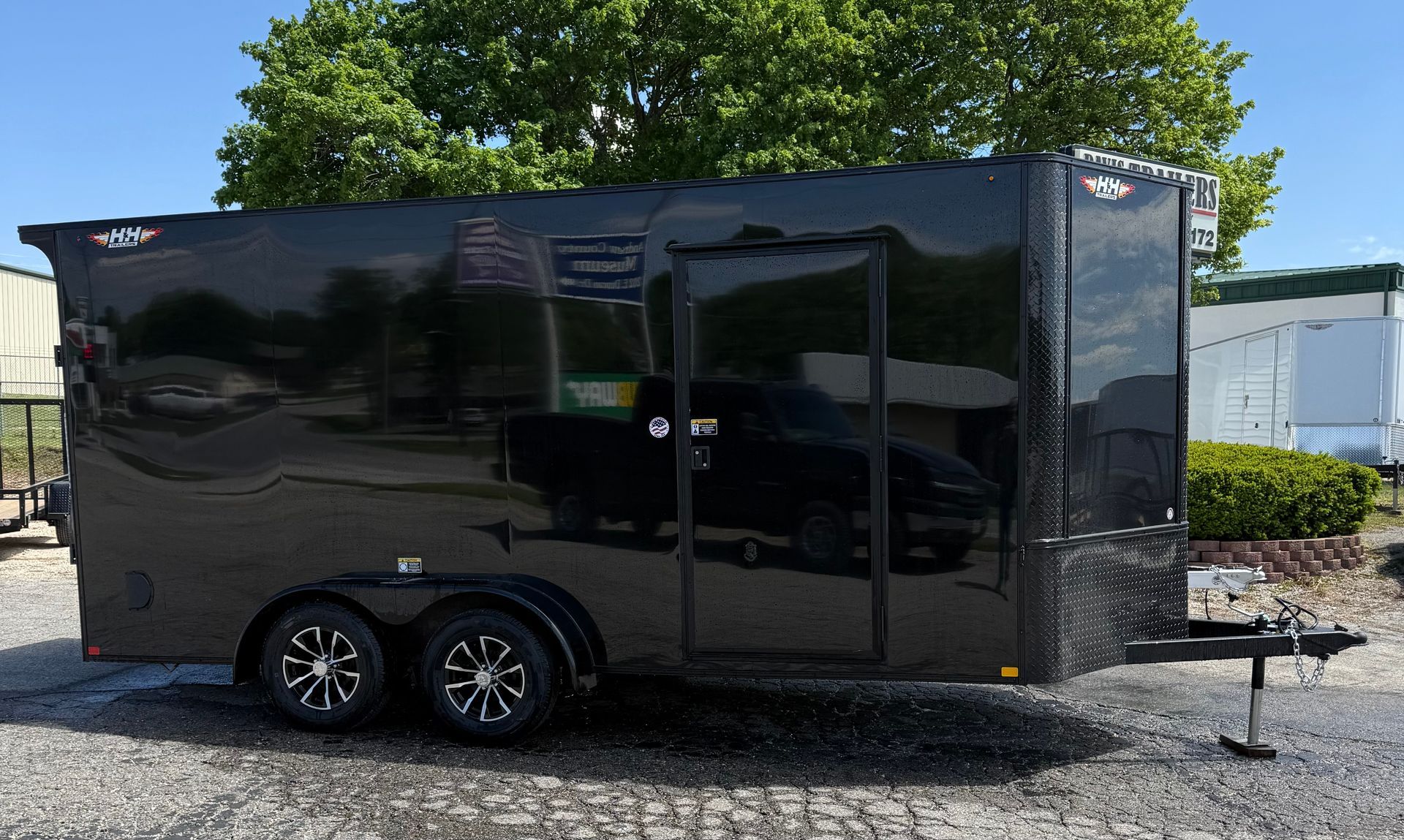 Black enclosed cargo trailer with two wheels, door, and silver trim