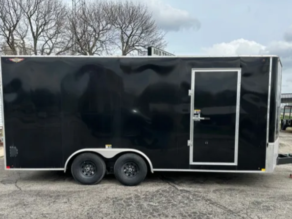 Black enclosed cargo trailer with a side door, gray wheels, parked on concrete