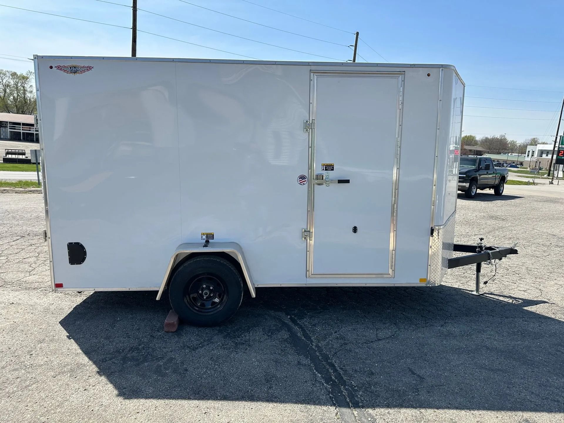 White enclosed cargo trailer with black tire on a paved lot