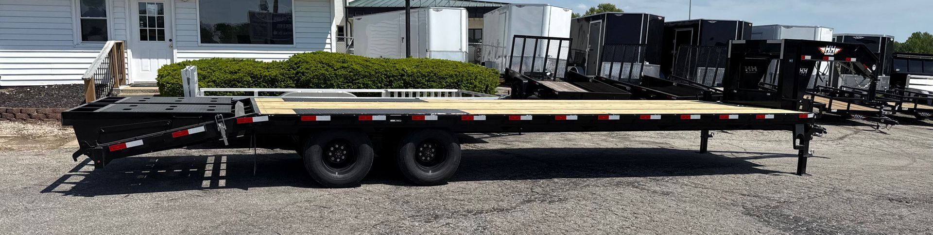 Black flatbed semi-trailer with hydraulic suspension and gooseneck hitch