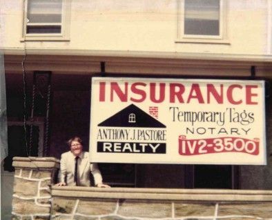 Man in suit stands under a sign for