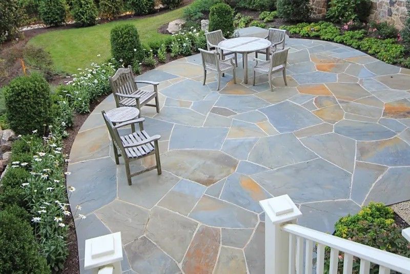 Stone patio with outdoor table and chairs in a landscaped garden