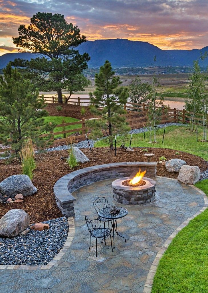 Stone patio with fire pit and chairs overlooking a valley at sunset