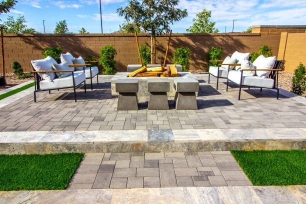 Outdoor patio with seating, stone fire pit, and landscaped yard in bright sunlight