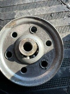 a close up of a metal wheel with holes in it on a black surface .