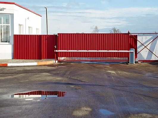 A red fence is in front of a white building