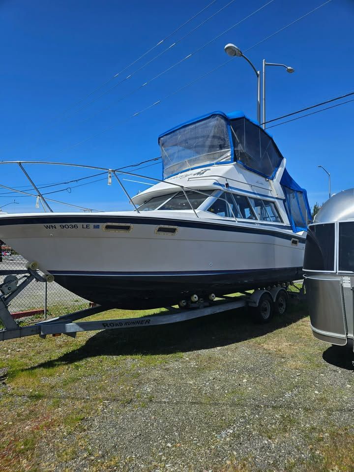 A boat is parked on a trailer next to an Airstream trailer.