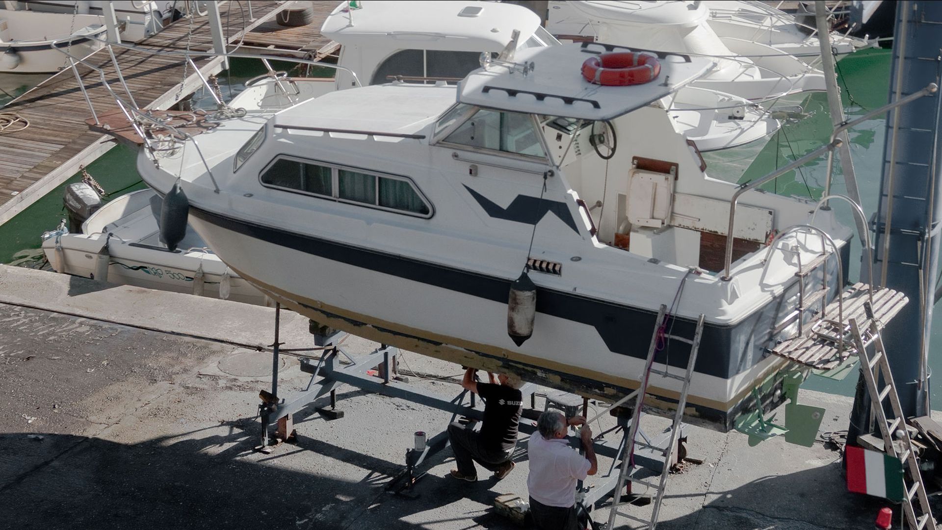 A man is standing next to a boat that has the word yacht on it