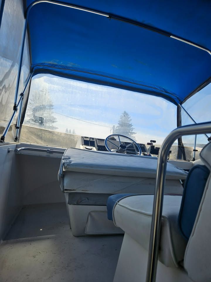The inside of a boat with a blue canopy and a steering wheel