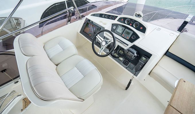 The cockpit of a boat with a steering wheel and a seat.