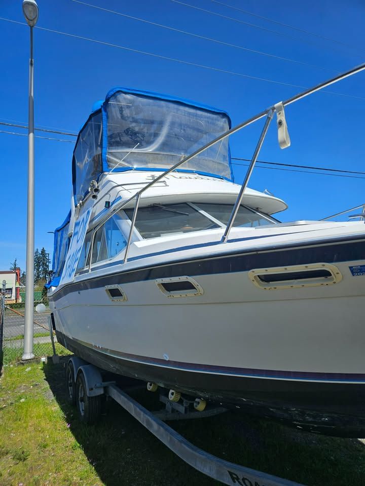 A white boat is parked on a trailer in the grass.