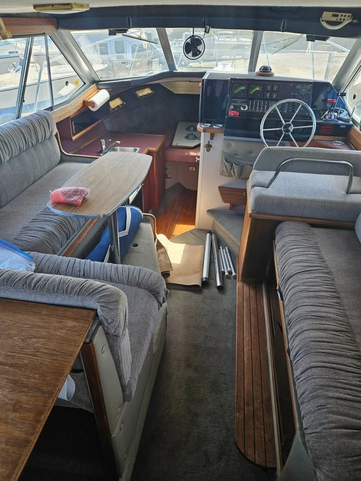 The inside of a boat with a steering wheel and a table.