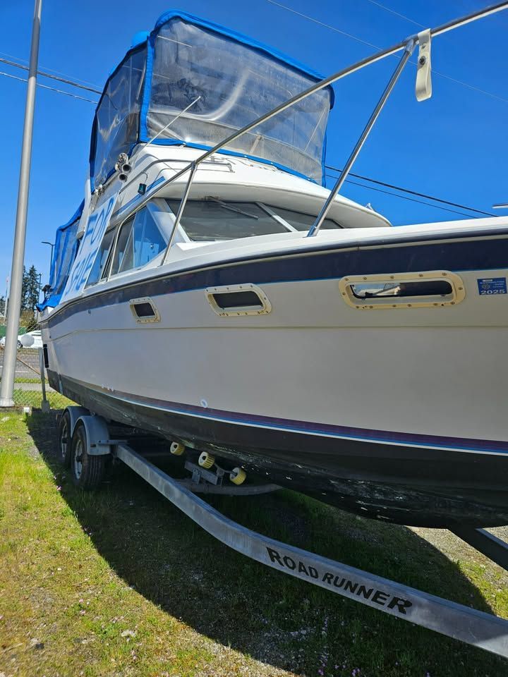 A boat is parked on a trailer in the grass.