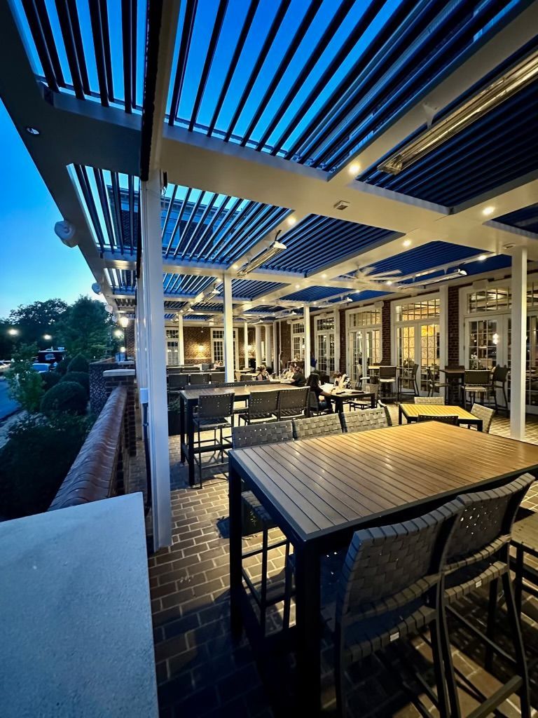 A restaurant with tables and chairs under a canopy at night