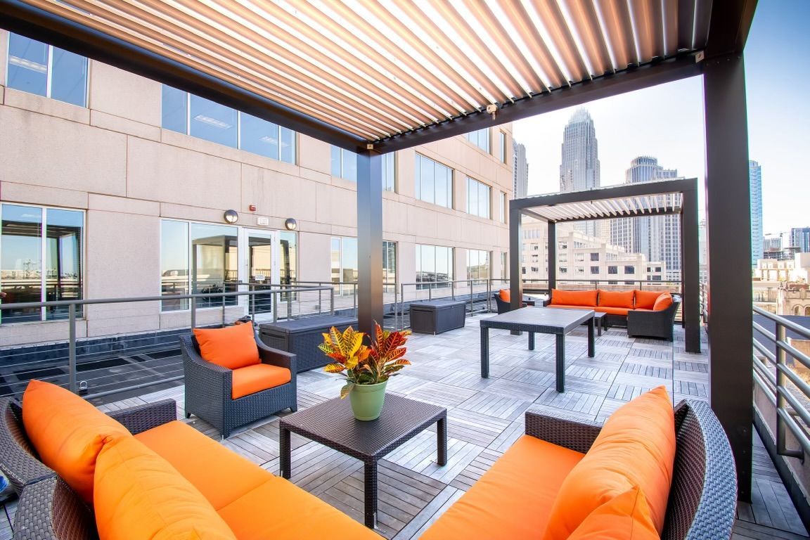 A patio with orange furniture and a pergola on top of it.